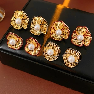 Macro shot of gold floral earrings with pearls in a black leather jewelry box with warm light