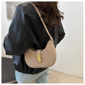 Detailed close-up of beige moon bag with gold buckle on a stylish leather jacket