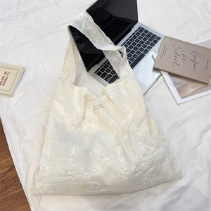 Detailed close-up of cream floral embroidery on the tote bag with minimalist logo label