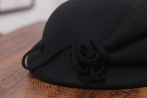 Détail d'un chapeau élégant en feutre de laine noir avec fleur en tissu et style rétro