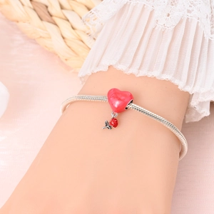 Pink heart charm with red rose pendant on silver snake chain worn on wrist