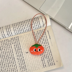 Detailed view of a cute plush tomato charm with green leaves on an open book background
