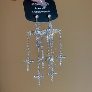 Macro shot of sparkling silver cross tassel earrings with brilliant rhinestone inlay detail