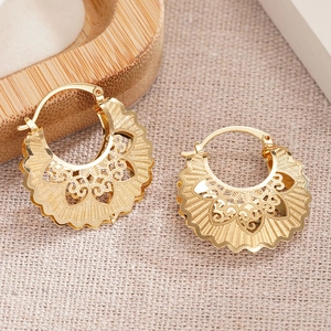 Elegant gold hollow flower hoop earrings with wavy texture on rustic linen background