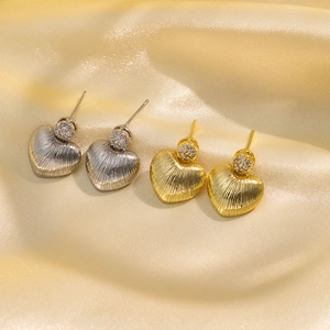 Elegant textured heart earrings in gold and silver with zircon detail on silk background