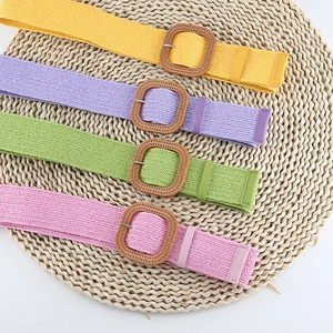 Close-up of woven straw belts in vibrant summer colors with vintage square buckles