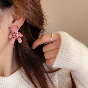 Close-up of pink flocked teddy bear earrings with sparkling rhinestones on a female model