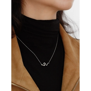 Close-up of a silver snake-shaped necklace with crystals worn on a model over a jacket