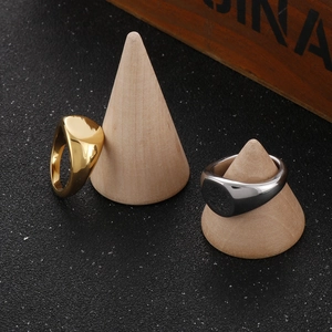 Polished stainless steel signet rings in gold and silver finish on wooden cone stands