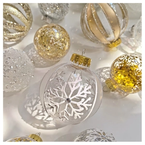 Detailed flat lay of transparent Christmas ball ornaments with gold glitter and snowflakes