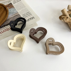 Matte heart-shaped hair claws in assorted neutral colors on a minimalist background