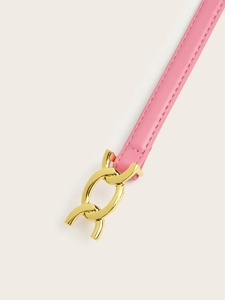 Detail of pink leather belt featuring a gold horsebit buckle against a plain background