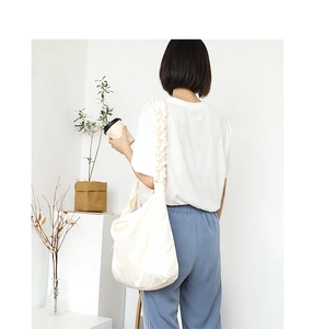 Detail of soft beige crossbody bag featuring a unique wide pleated cloud-style shoulder strap