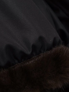 Detailed macro view of black woven fabric with dark brown faux fur trim on winter jacket
