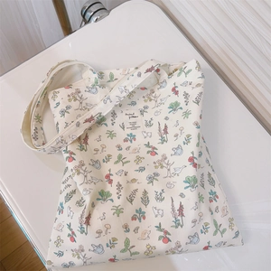 Close-up of floral animal patterns and logo on cream canvas shoulder tote bag
