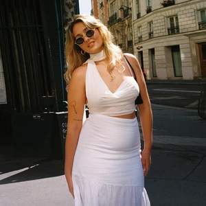 Outdoor view of a white halter neck crop top and matching long skirt vacation set
