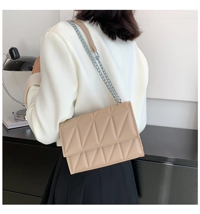 Close-up of beige quilted leather crossbody bag with silver chain strap on a model