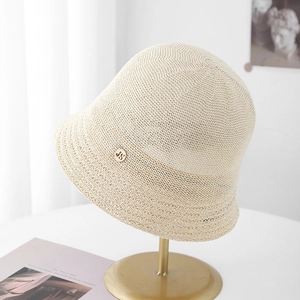 Chapeau cloche en maille beige pour femme avec emblème doré sur support doré