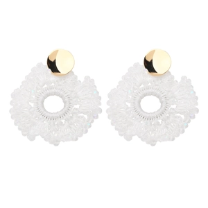 Close-up of handmade white woven bohemian hoop earrings with golden studs and sequins