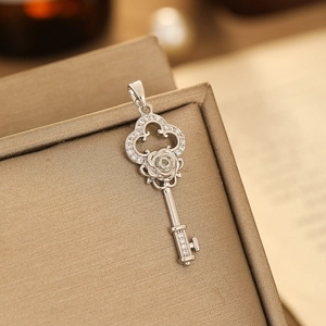 Macro shot of silver key pendant with rose relief and micro-inlaid cubic zirconia