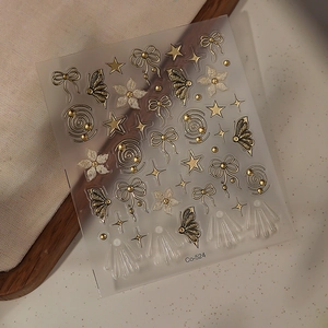 Macro detail of gold butterfly and bow nail stickers with premium embossed texture