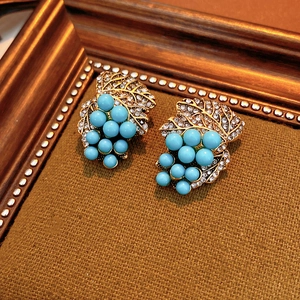 Detail of vintage gold-tone grape earrings featuring blue beads and sparkling rhinestones