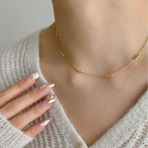 Minimalist 925 sterling silver gold beaded necklace worn on a soft knit cardigan