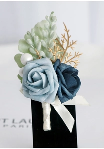 Close-up of blue rose boutonniere with gold accents and pearls for wedding attire
