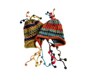 Detail of striped knit beanies featuring colorful tassels and decorative wool pom-poms