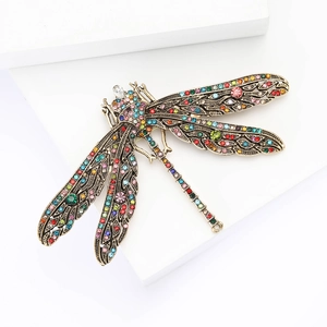 Vintage bronze dragonfly brooch with colorful rhinestones on a minimalist white background