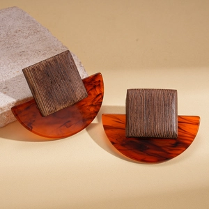 Geometrische Vintage-Ohrringe aus Holz und Bernsteinharz auf beigefarbenem Lederhintergrund