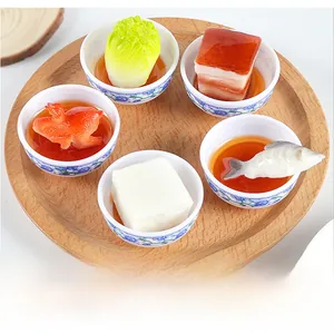 Detail view of five miniature food models in blue and white bowls on a wooden tray