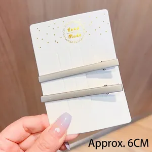 Détail de deux pinces à cheveux gris mat sur carte faite main, longueur 6 cm chacune