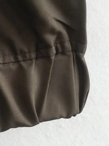 Gros plan détaillé des poignets élastiques et de la texture en sergé olive de la veste