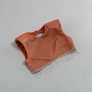 Dettaglio del crop top arancione metallizzato con orlo a frange di strass argentati