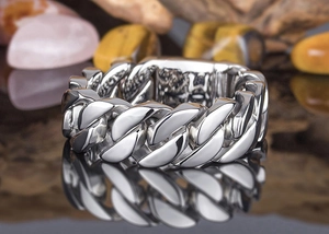 Macro shot of silver stainless steel Cuban link ring with crisp reflections on a mirror