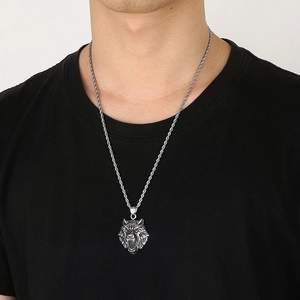 Close-up of a silver wolf head pendant with a twisted chain on a male model's neck