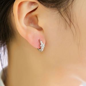 Gros plan de boucles d'oreilles cœur en argent avec cristaux portées par un mannequin