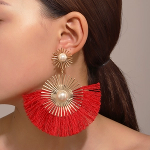 Close-up of bohemian fan-shaped red fringe earrings with gold metal and pearls on a model