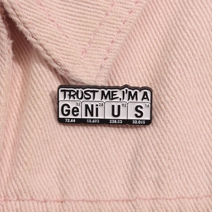 Close-up of Trust Me I'm a Genius metal pin badge on pink denim fabric material