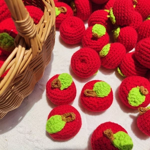 Macro shot of handmade crochet red apple pendants with green leaves in a rustic basket