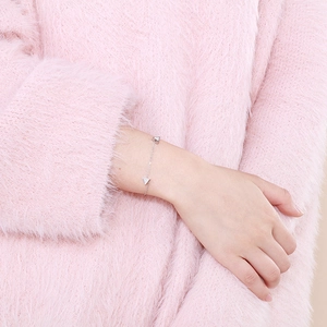 Close-up of silver chain bracelet with micro-paved triangular zircon charms on wrist