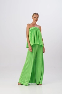 Dettaglio del tessuto plissettato verde brillante su top a fascia e pantaloni larghi