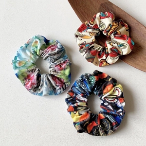 Three premium printed yoga headbands with floral and butterfly patterns on a wooden tray