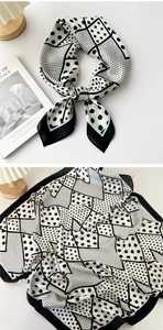Detail view of monochrome silk scarf with geometric polka dot pattern and smooth texture