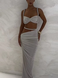 Detail of light grey ribbed knit crop top and high waist slit skirt with rope accents