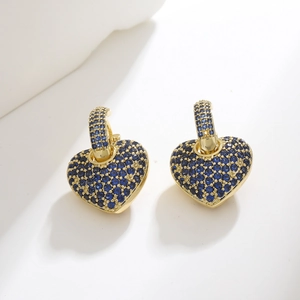 Close-up of gold earrings featuring heart charms encrusted with blue crystals