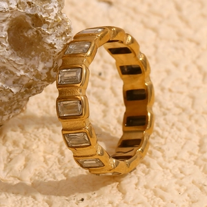 Macro shot of gold square zircon ring on crystal rock with sand background