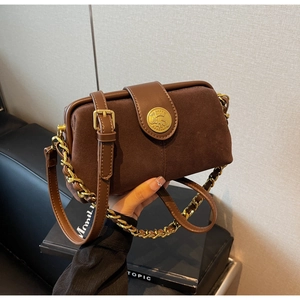 Detail of a dark brown suede crossbody bag with gold chain and vintage metal buckle