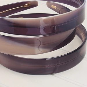 Detail of 2.2cm vintage acetate headbands in purple and beige on white wood